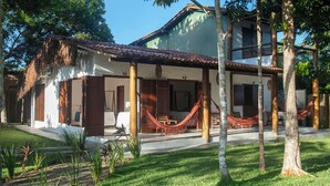 A house with a thatched roof, wooden pillars, and a hammock. - Pousada Lua Cheia Praia do Espelho (Porto Seguro)