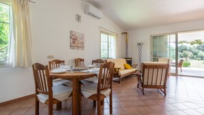 Un'area pranzo con un tavolo e sedie in legno, un divano e un'ampia finestra con tende.