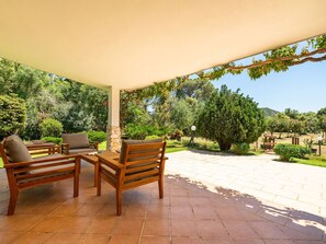 A covered patio with wooden furniture and a stone pillar. - Malù House by Interhome (Villasimius)
