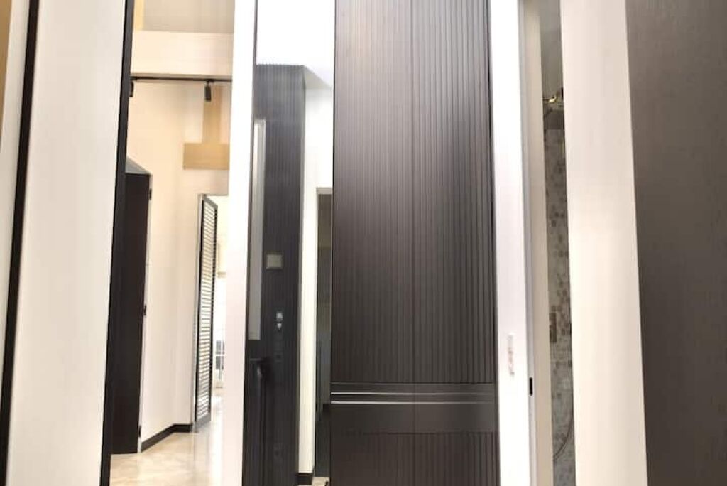 Un corridoio con una porta in legno scuro, un muro bianco e un telaio nero.