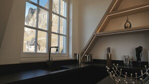 Une cuisine moderne dotée d’une grande fenêtre, d’un plan de travail noir et d’un évier en acier inoxydable.