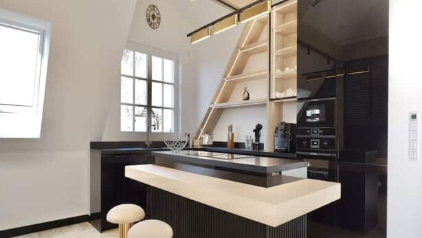 Une cuisine moderne dotée d’un îlot central, de tabourets de bar et d’étagères intégrées.