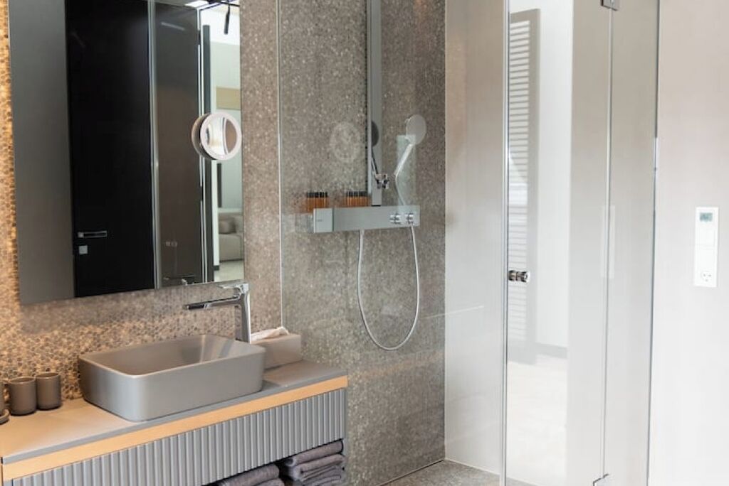 Een moderne badkamer met een rechthoekig wastafelmeubel, een spiegel en een douche met een handdouche.