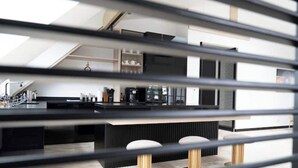 Une cuisine moderne dotée d’un îlot central, de plans de travail noirs et d’appareils électroménagers en acier inoxydable.
