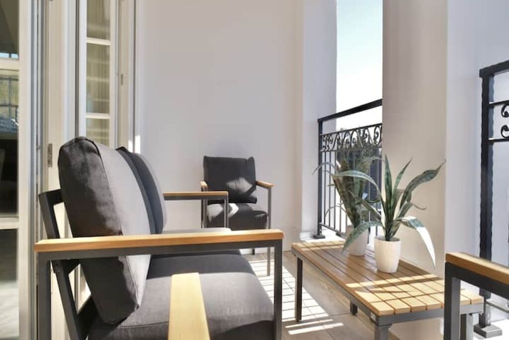 A balcony with a sofa, armchairs, a small table, and a potted plant.