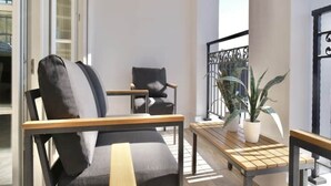Un balcon avec un canapé, des fauteuils, une petite table et une plante en pot.
