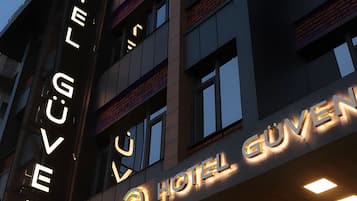 Letrero de hotel con letras iluminadas que deletrean 'HOTEL GUYEN' sobre un cielo oscuro.