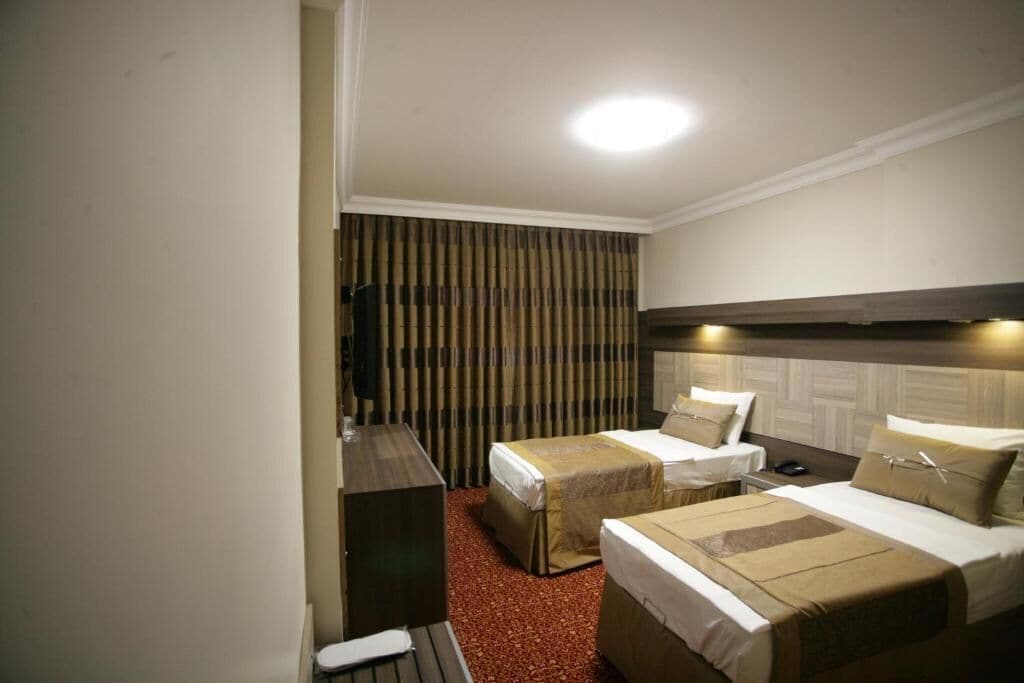 Una habitación de hotel con dos camas individuales, un escritorio y una televisión.