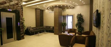 A lobby with a curved ceiling, a sofa, a coffee table, and a television.