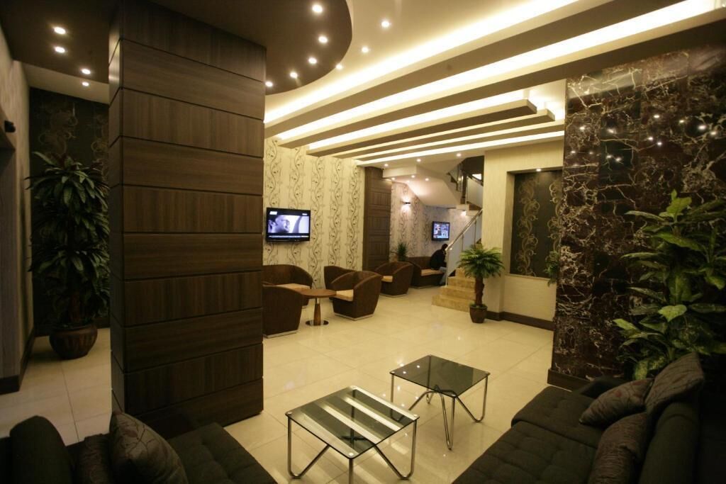 Un vestíbulo moderno con asientos, una escalera y una pantalla de televisión.