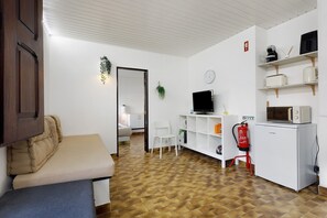 Ein Zimmer mit einer Couch, einem Fernseher, einer Mikrowelle und einem Feuerlöscher.