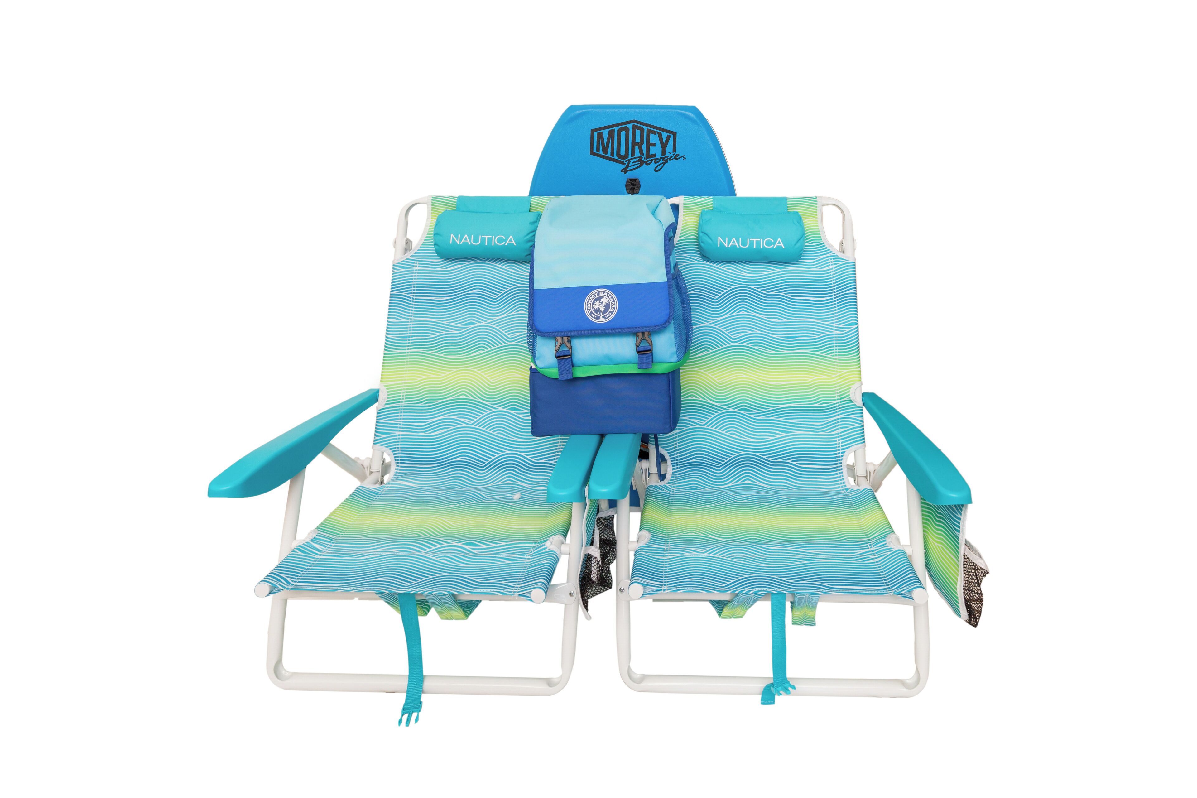 A beach chair with a blue and green striped cushion, a small blue bag, and the word "NAUTICA" on the armrests.