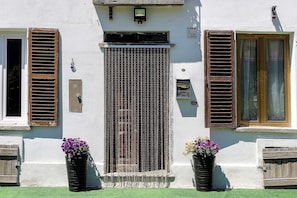 Un edificio con facciata bianca, una porta in legno e persiane alle finestre.