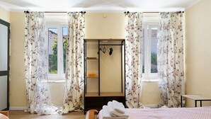 Une chambre à coucher avec un lit, un plancher en bois, une fenêtre avec des rideaux et une armoire.