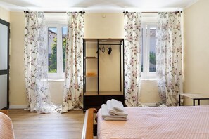 Una camera da letto con un letto, pavimento in legno, una finestra con tende e un armadio.