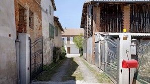 Une ruelle étroite avec une boîte aux lettres rouge, un portail en métal et un bâtiment en briques surmonté d’un toit en tuiles.