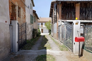 Un vialetto stretto con una cassetta delle lettere rossa, un cancello in metallo e un edificio in mattoni con tetto in tegole.