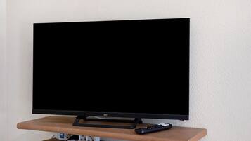 A television on a wooden stand with a remote control beside it.