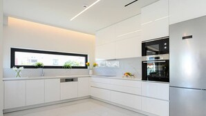 Eine moderne Küche mit weißen Schränken, einem Edelstahlkühlschrank und einem eingebauten Backofen.