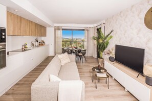 A modern living room with a sofa, a TV, and a dining area with a table and chairs. - Modern 2 Bedroom 2 bathroom Apartment - Sleeps 4 (Xàbia)