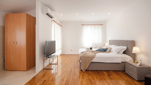 A bedroom with a bed, bedside table, TV, wardrobe, and an air conditioning unit. - Superior 1-bedroom S2 (Rovinj)