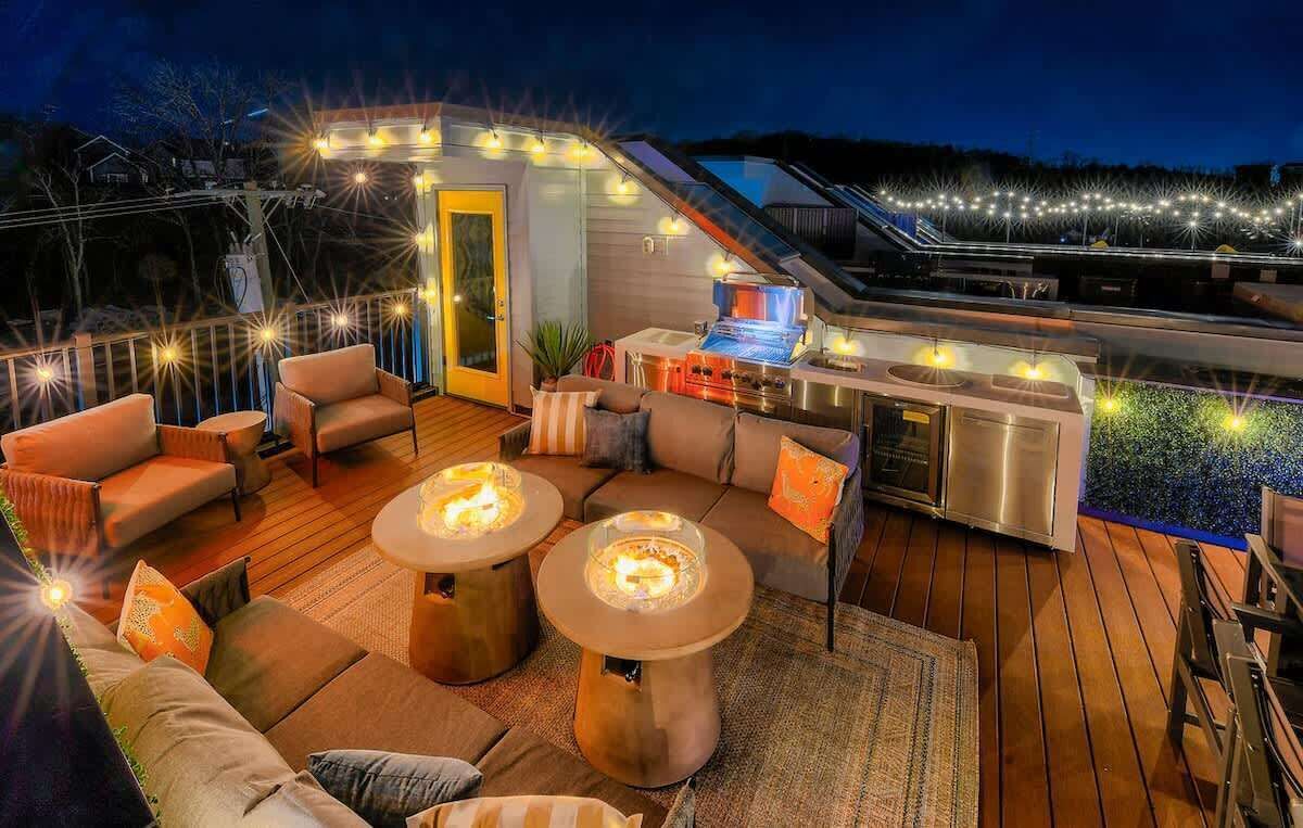 An outdoor deck with seating, a grill, and string lights.