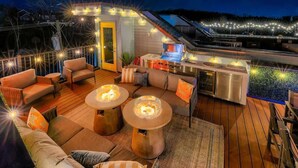 An outdoor deck with seating, a grill, and string lights. - Pool- Hot Tub- Bar! Rooftop Fire Pit 9 Beds (Nashville)