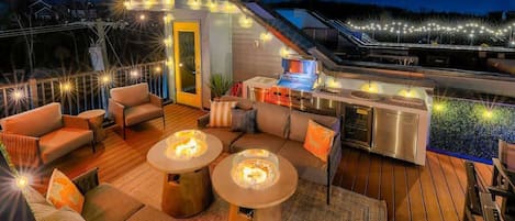 An outdoor deck with seating, a grill, and string lights.