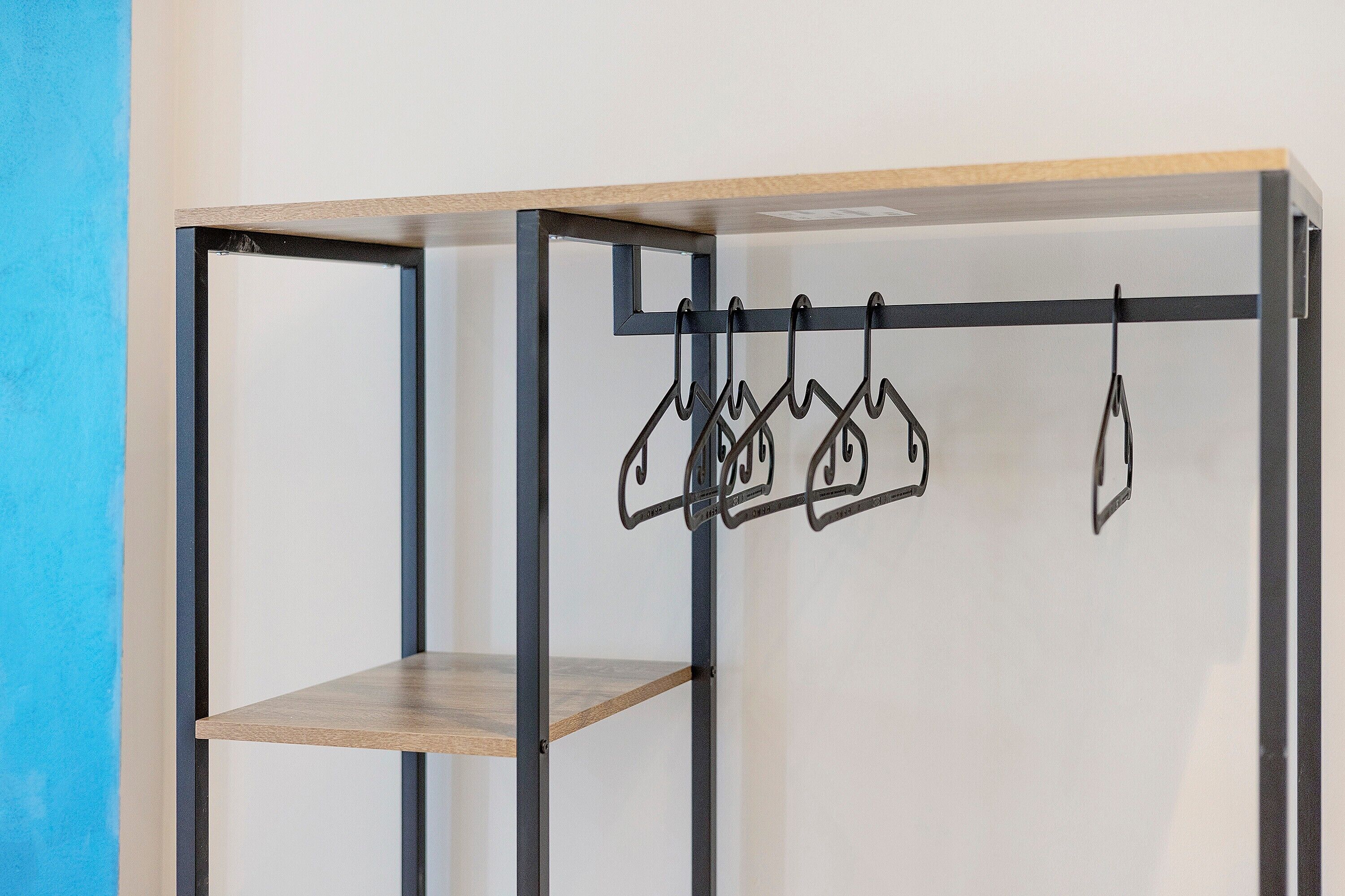 Une pièce dont la structure est en métal, avec une étagère en bois et un portant à vêtements.