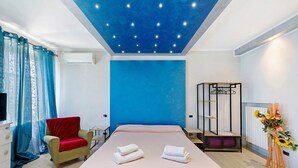 Une chambre à coucher comprenant un lit, une chaise, une commode, un climatiseur, un miroir et un radiateur fixé au mur.