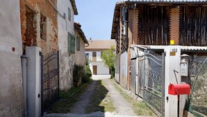 Un carreró estret amb una cassaposta vermella, una reixa metàl·lica i un edifici de maó amb teulada de rajola.