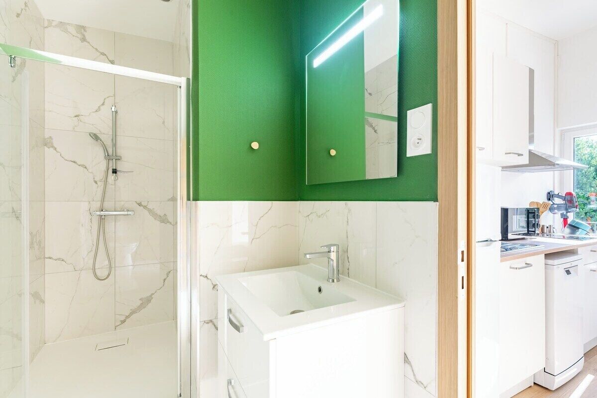 Une salle de bain avec une douche, un lavabo et un miroir.