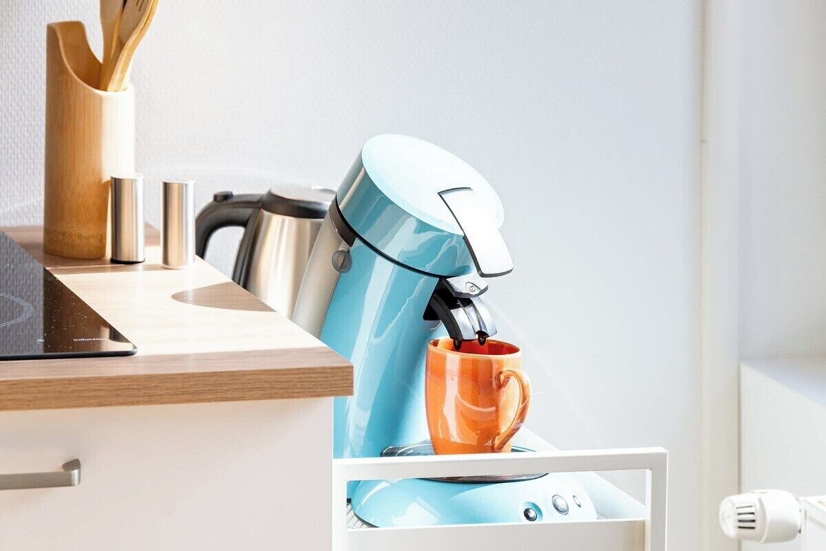 A coffee machine dispensing coffee into a mug, a knife block, and a cup on a countertop.
