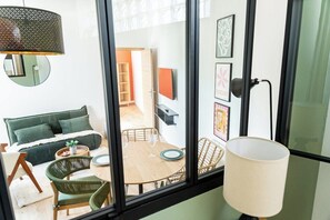 A modern room with a sofa, dining table, chairs, a lamp, and artwork on the wall. - Le Pascal - Bright & Stylish 3-Bedroom Flat (Dijon)
