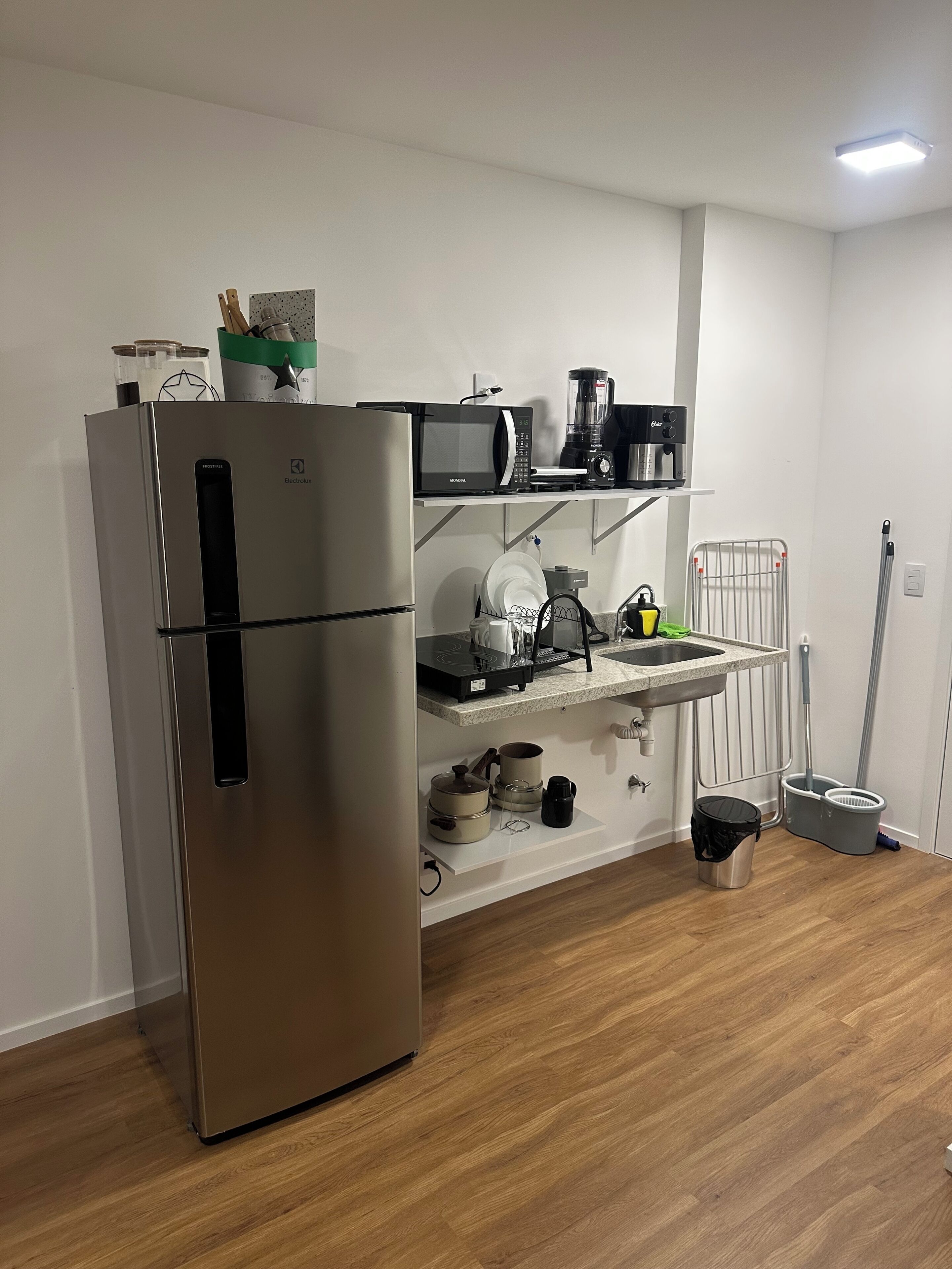 A modern kitchen with a stainless steel refrigerator, a microwave, a coffee maker, and a kettle on the countertop.