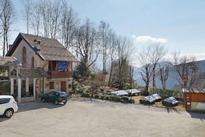 A building with a sloped roof, a visible entrance, and a parking area with cars.