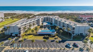 A multi-story hotel with a pool, parking lot, and beachfront view. - Captains Quarters 318: charming, steps to ocean and pool (Saint Augustine)