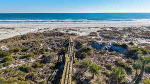 A coastal boardwalk leading to the beach with sparse vegetation and a clear view of the ocean. - Captains Quarters 318: charming, steps to ocean and pool (Saint Augustine)
