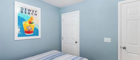 A bedroom with a bed, a framed poster, and two white doors.