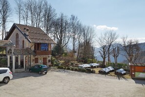 A building with a sloped roof, a covered outdoor seating area, and a view of trees and mountains.