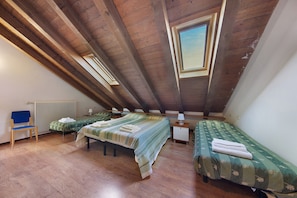 Une chambre avec deux lits, une chaise, une table de chevet et une fenêtre.