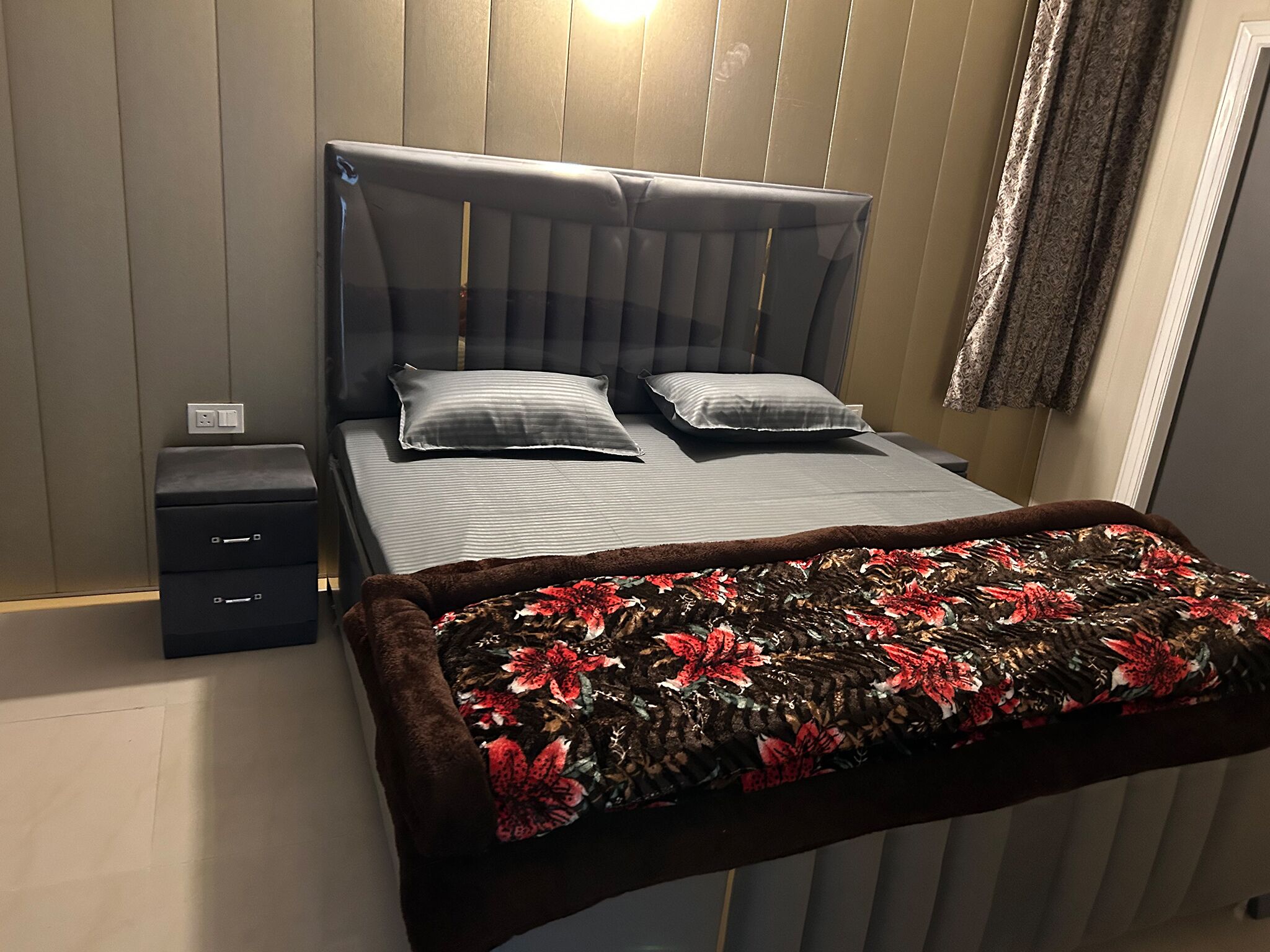 Un dormitorio ordenado con una cama, dos mesitas de noche y un edredón decorativo.