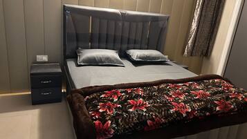 Un dormitorio ordenado con una cama, dos mesitas de noche y un edredón decorativo.