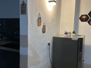 Una cocina con refrigerador, una lámpara en la pared y un letrero que dice 'Taste is Love'.