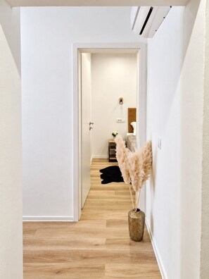 A hallway with a wooden floor, a white door, and a wall-mounted air vent. - Apartment Perla (Vir)