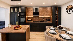 A modern kitchen with a central island, built-in appliances, and a dining area with a round table set for four. - Apartment Perla (Vir)