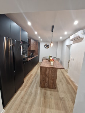 A modern kitchen with a central island, black appliances, and a wooden floor. - Apartment Perla (Vir)