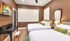 Une chambre d’hôtel avec deux lits, un bureau, une chaise, un grand miroir et un tableau au mur.