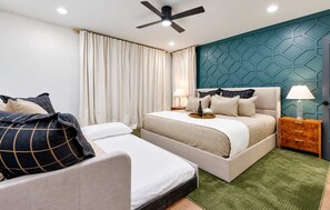 A hotel room with a bed, a smaller bed, a nightstand, a lamp, a ceiling fan, and a green carpet. - Pool - Hot Tub - Golf-Fire pit 14 Beds (Nashville)