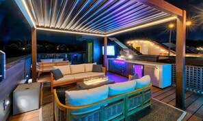 An outdoor deck with a sofa, chairs, and a bar area with a television. - Pool - Hot Tub - Golf-Fire pit 14 Beds (Nashville)